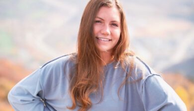 Smiling woman in blue sweater outdoors.