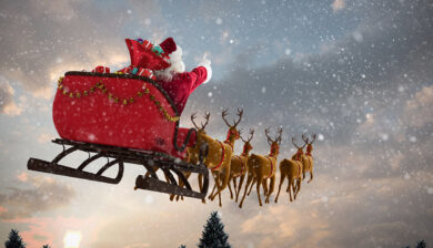 Santa in sleigh flying with reindeer.